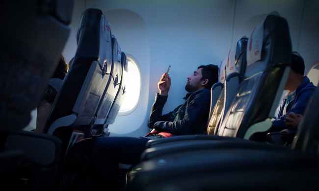 Person sitting inside an airplane using a phone